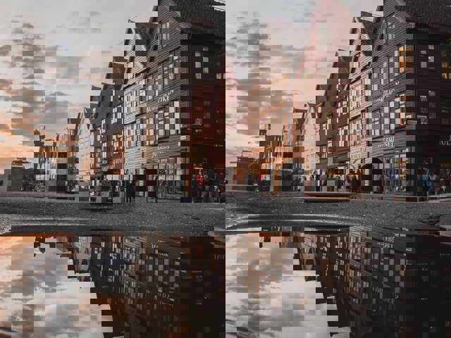 Bryggen i Bergen som speiler seg i en sølepytt. Foto: Leonard Rb på Unsplash.com