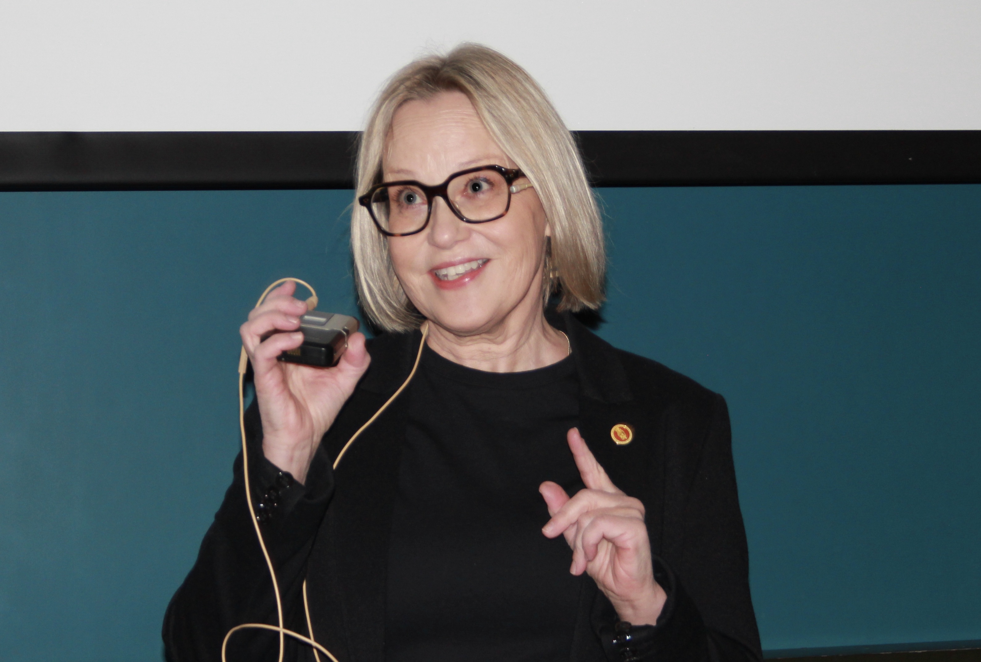 Kvinne med lyst h&aring;r som holder en tr&aring;dl&oslash;s mikrofon