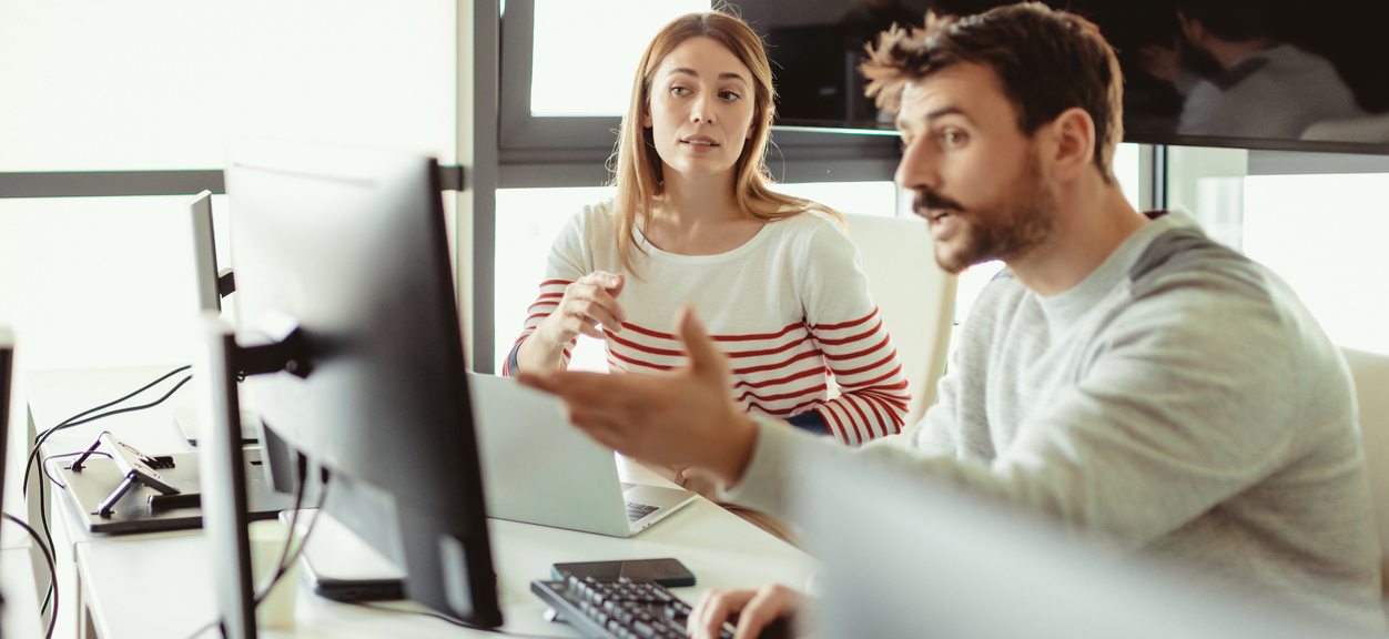 Bilde av dame og mann ved en PC. Mannen forklarer damen noe. istockphoto