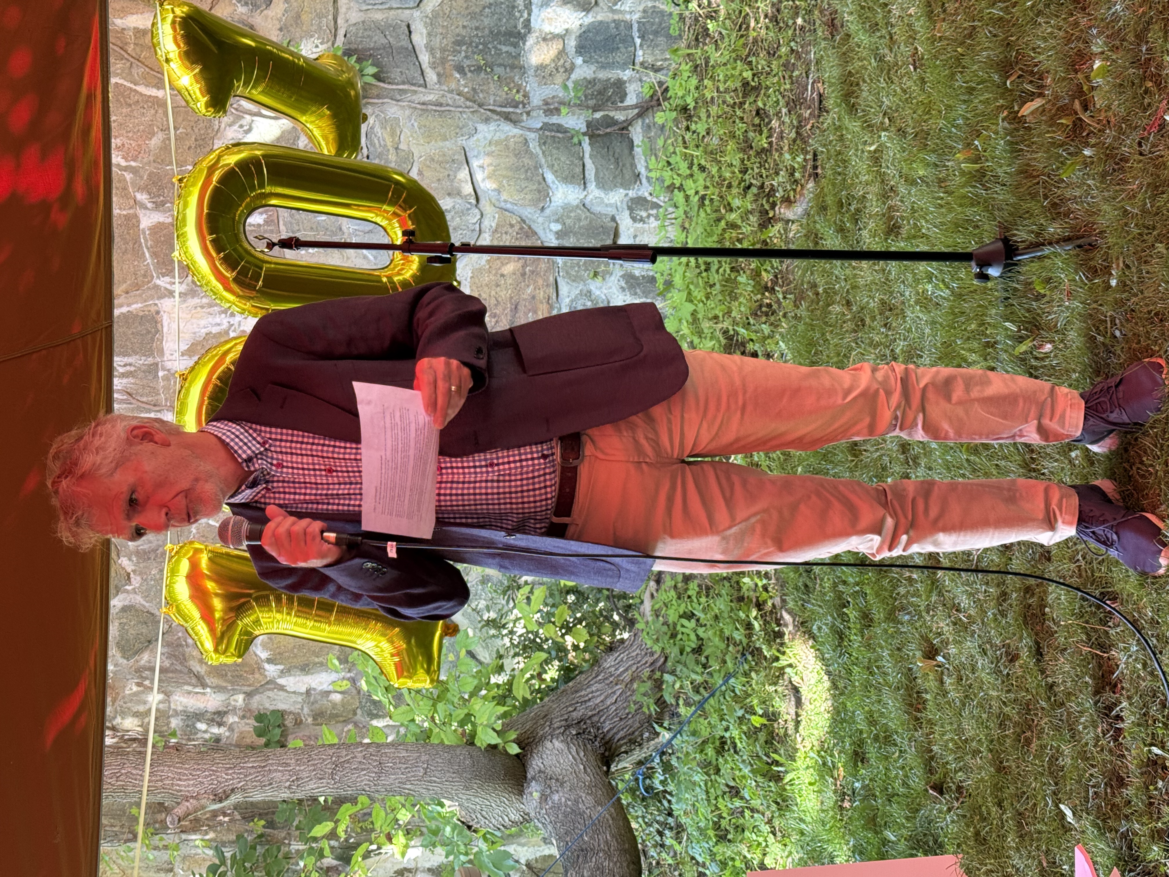 En mann med en mikrofon. gullballonger i bakgrunnen