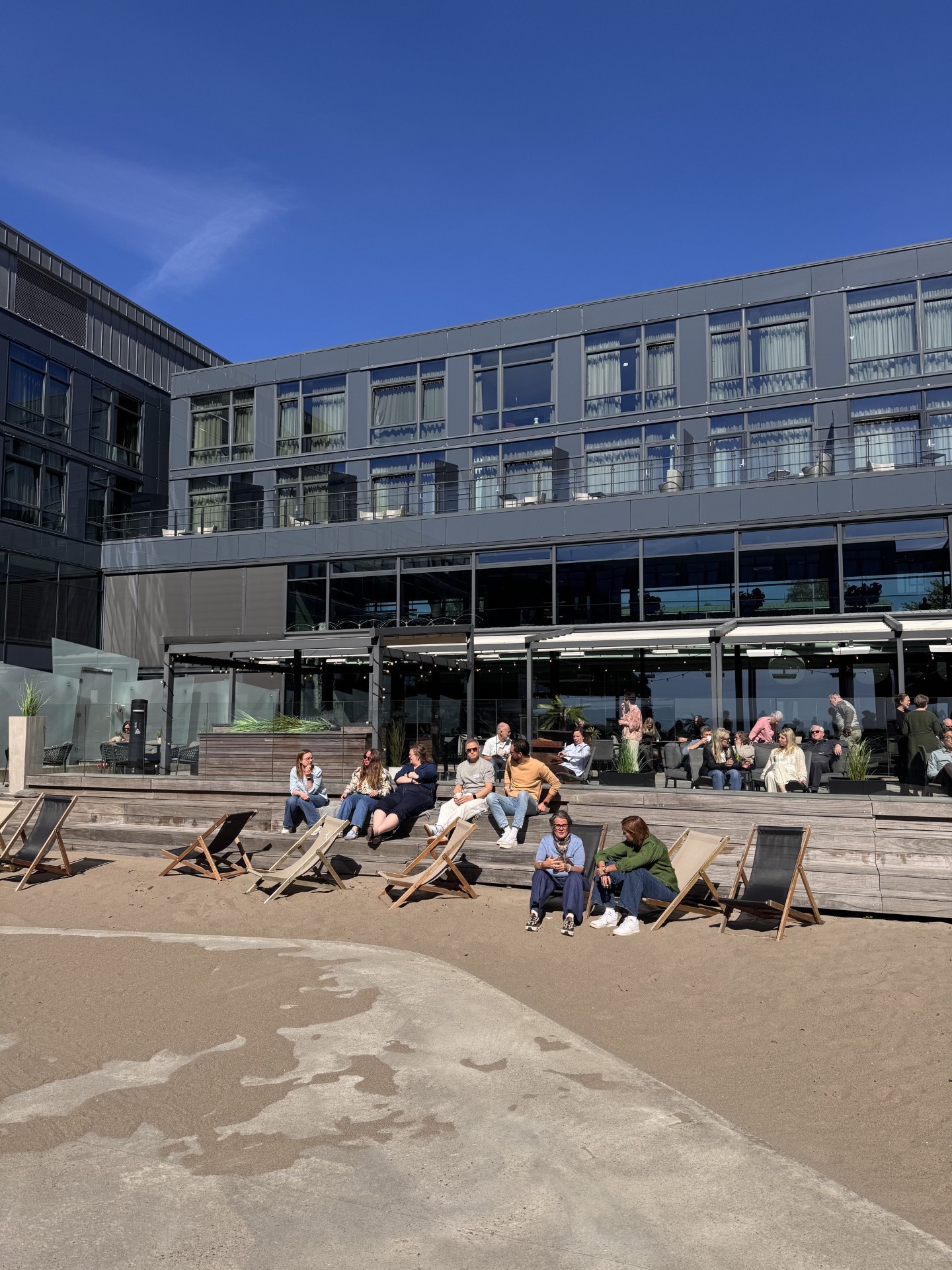 Folk i sola ved sanden utenfor Farris bad