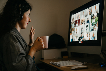 En kvinne med en kaffkopp som sitter foran en datamaskin med et digitalt møte. Foto: Istockphoto.com