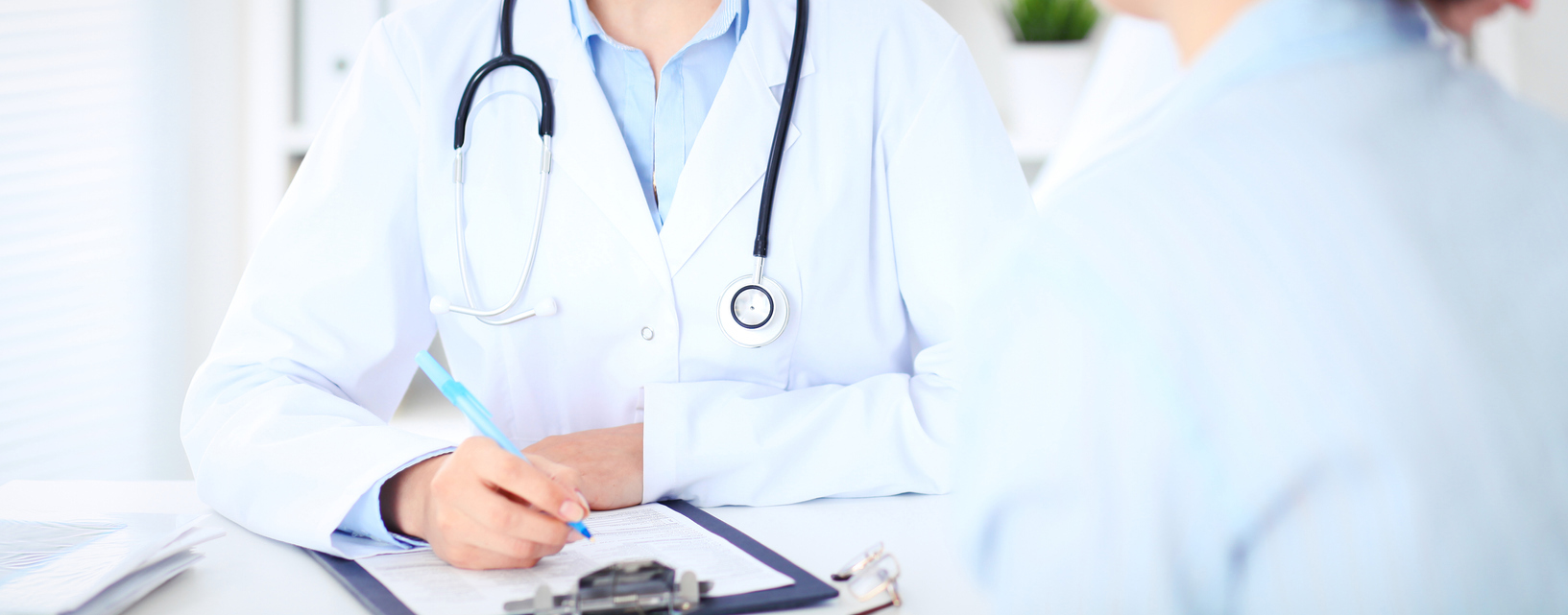 Lege som tar notater på en blokk mens pasienten snakker. Foto: Istockphoto.com