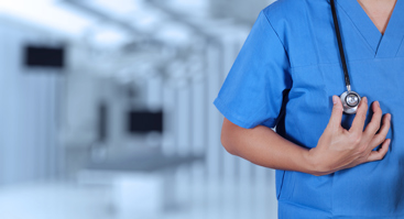 Nærbilde av overkropp til lege i blå skjorte med stetoskop hengende rundt halsen. Foto: Colourbox. 