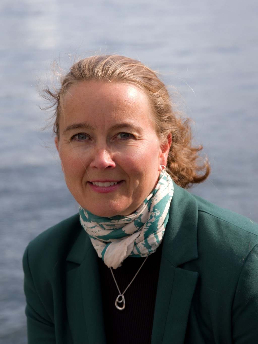 Dame med grønn dressjakke og skjerf hav i bakgrunnen. Ingvild Eide Graff. Foto: Privat