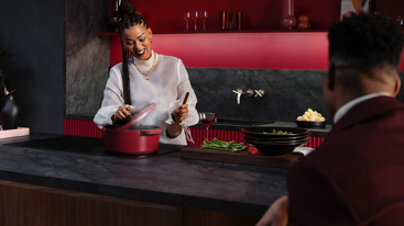 En dame som ser i en kjele på en AEG ovn. Foto: Akademikerne pluss