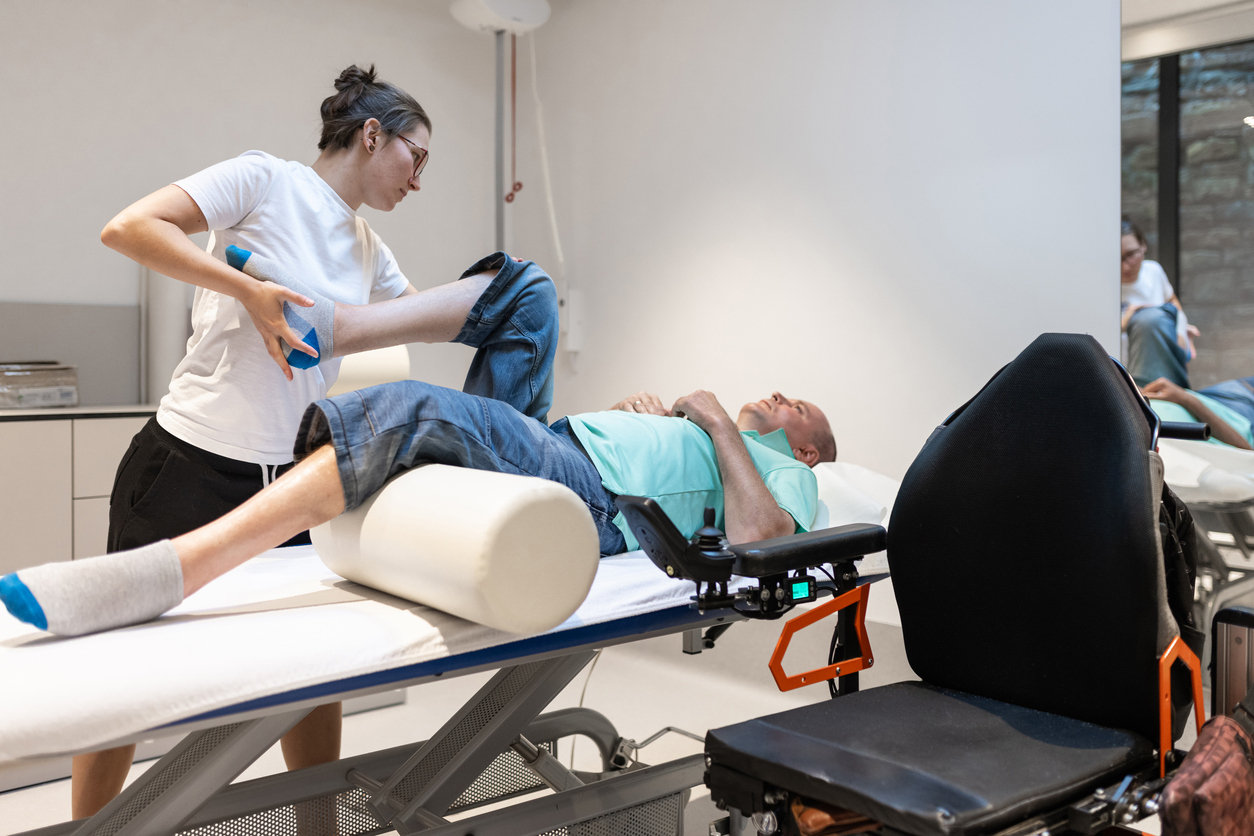 En mann på en benk med fysisk handikap som får behandling av en fysioterapaut. Foto: Istockphoto.com/Mr Vito