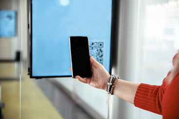 En hånd med en mobil som scanner en QR-kode på en skjerm. Foto: Istockphoto.com/PhotoLife94