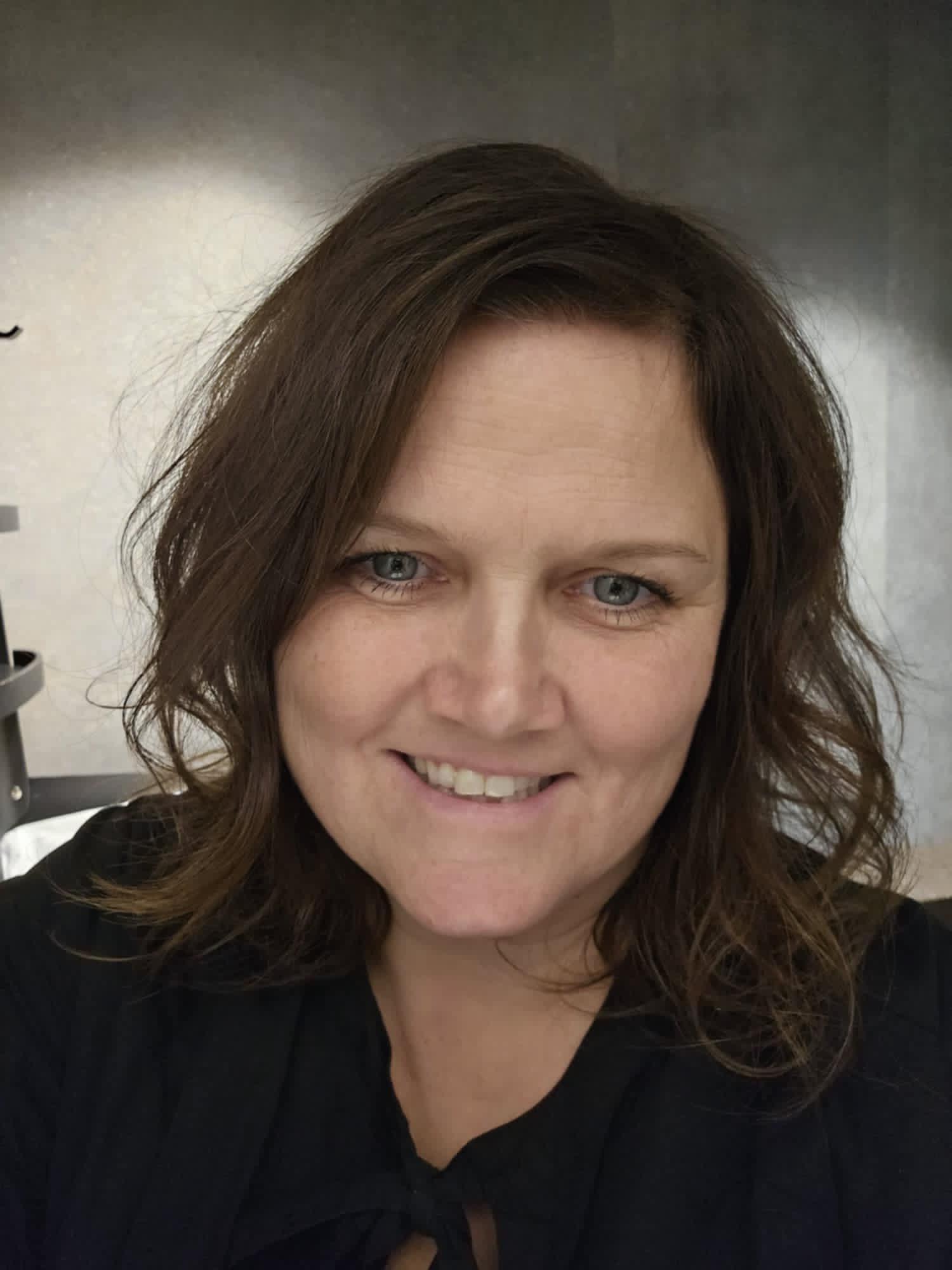 En smilende kvinne med m&oslash;rkt h&aring;r.