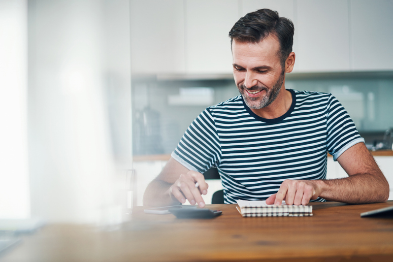 Mann som sitter med en kalkulator og en blokk på bordet. Foto: Istockphoto.com/BartekSzewczyk