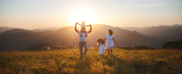 En familie på fire som går over en eng i solnedgang. Foto: Istockphoto.com/evgenyatamanenko