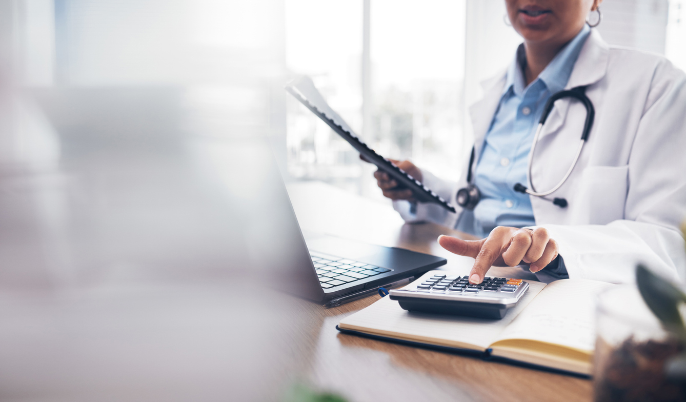 Kvinnelig lege ved en pult som trykker på en kalkulator. Foto: Istockphoto.com/Jacob Wackerhausen
